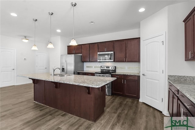 kitchen with appliances with stainless steel finishes, tasteful backsplash, a sink, and dark wood-style floors