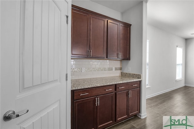 kitchen with baseboards, dark wood finished floors, decorative backsplash, and light stone countertops