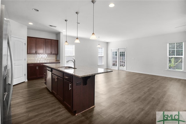 kitchen featuring stainless steel appliances, a sink, a kitchen breakfast bar, backsplash, and dark wood finished floors