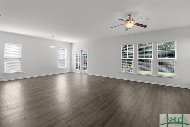 unfurnished living room with dark wood-style floors, a ceiling fan, and baseboards