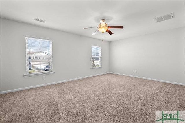 carpeted spare room with a ceiling fan, visible vents, and baseboards