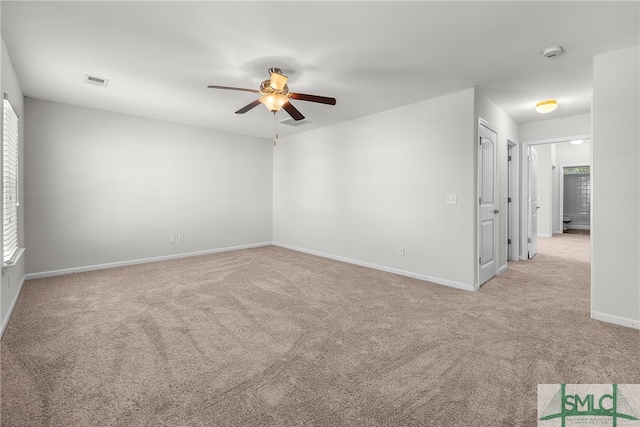 spare room with ceiling fan, visible vents, baseboards, and light colored carpet