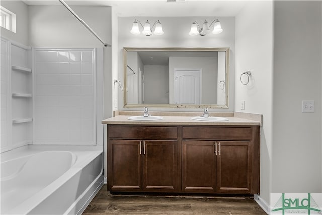 full bath with double vanity, wood finished floors, and a sink