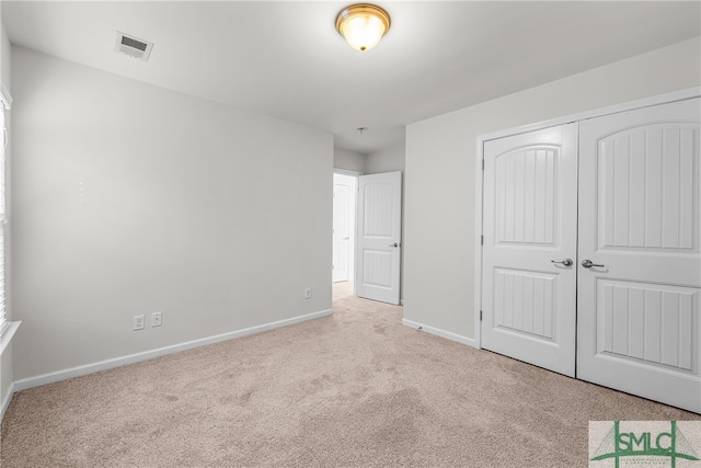 unfurnished bedroom with carpet, a closet, visible vents, and baseboards