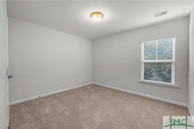 spare room with carpet floors, visible vents, and baseboards