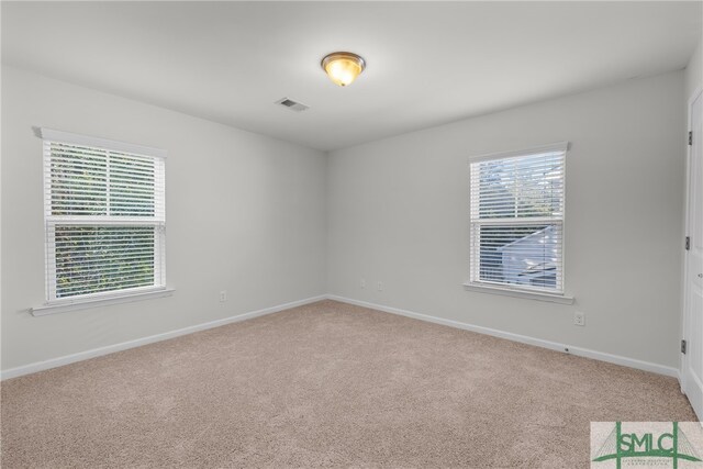 carpeted empty room featuring visible vents, plenty of natural light, and baseboards