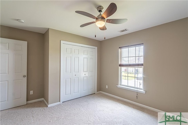 unfurnished bedroom with light carpet, a ceiling fan, visible vents, baseboards, and a closet