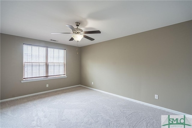 carpeted spare room featuring ceiling fan, visible vents, and baseboards