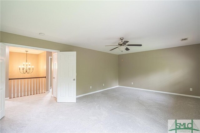 empty room with ceiling fan with notable chandelier and light carpet