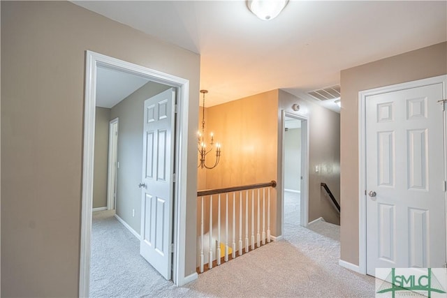 corridor featuring light carpet, baseboards, visible vents, an inviting chandelier, and an upstairs landing