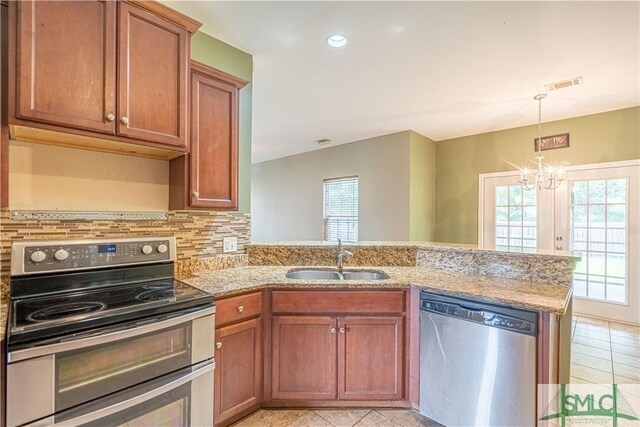 kitchen with backsplash, stainless steel appliances, a healthy amount of sunlight, kitchen peninsula, and light tile patterned flooring