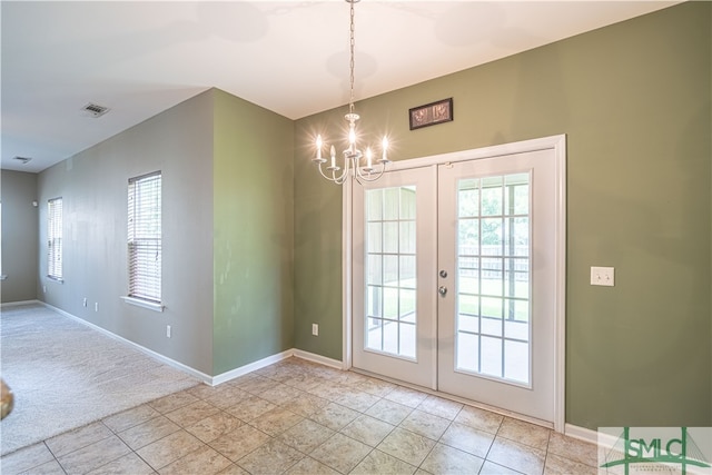 doorway featuring a wealth of natural light, a chandelier, light tile patterned floors, and french doors