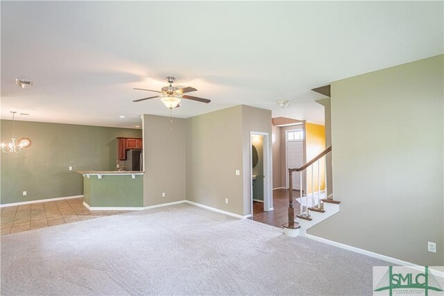 empty room with light colored carpet and ceiling fan with notable chandelier