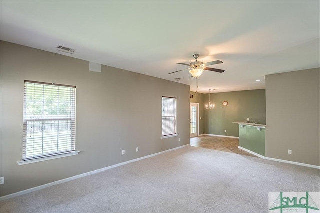 spare room featuring light carpet, baseboards, visible vents, and ceiling fan with notable chandelier