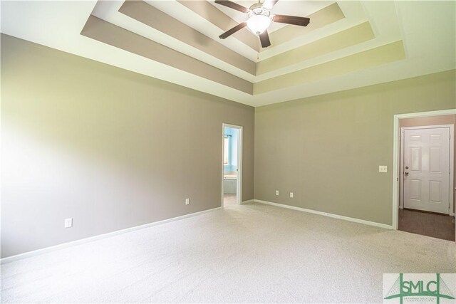 spare room featuring ceiling fan, a raised ceiling, and carpet