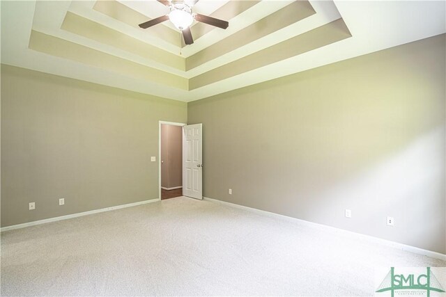 carpeted empty room with ceiling fan, a raised ceiling, and a high ceiling