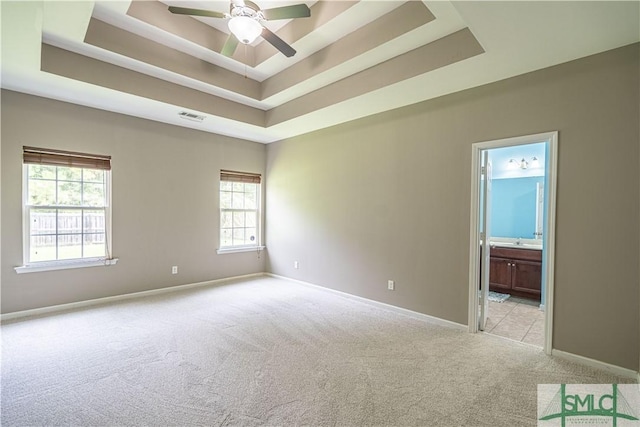 unfurnished room featuring baseboards, a tray ceiling, visible vents, and light colored carpet