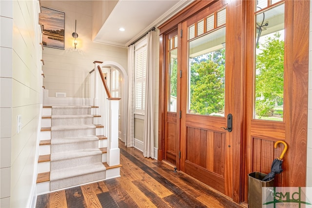 doorway to outside with ornamental molding, wooden walls, and dark hardwood / wood-style floors