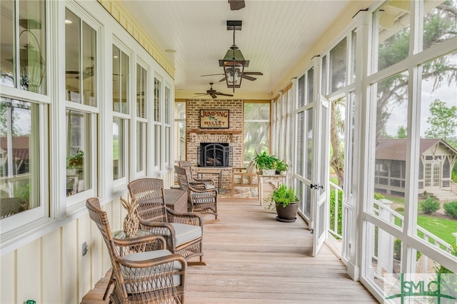 sunroom with ceiling fan and a brick fireplace