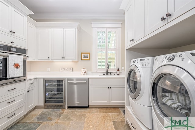 laundry area with cabinets, wine cooler, washing machine and dryer, crown molding, and sink