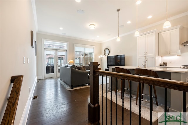 kitchen with white cabinetry, dark wood-type flooring, pendant lighting, ornamental molding, and a breakfast bar