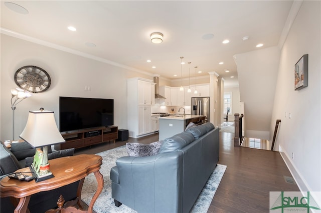 living room featuring sink, dark hardwood / wood-style flooring, and ornamental molding