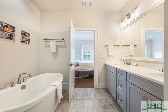 bathroom with tile patterned flooring, a tub, ornamental molding, and vanity