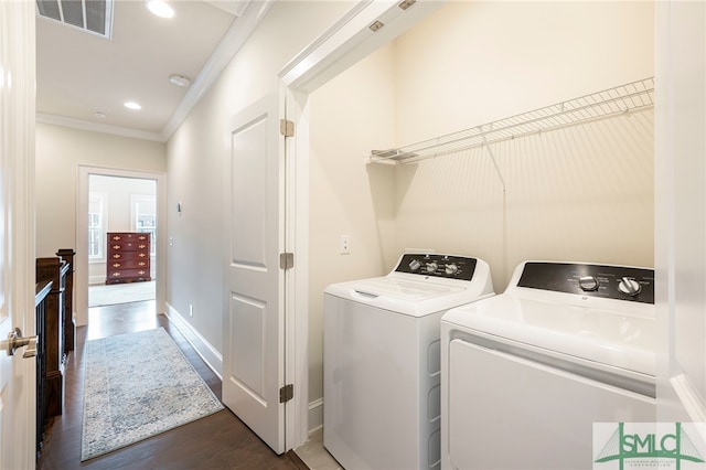 laundry room with crown molding, washing machine and dryer, and dark hardwood / wood-style floors