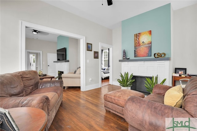 living room featuring a fireplace, dark hardwood / wood-style flooring, and ceiling fan