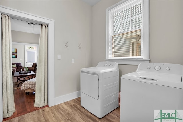 laundry room featuring a healthy amount of sunlight, washing machine and dryer, and light wood-type flooring