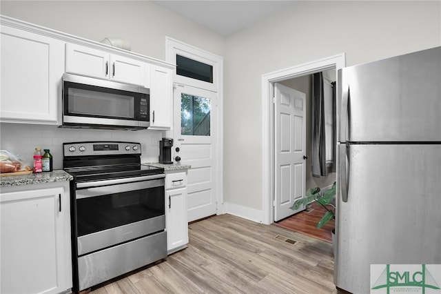 kitchen with light stone countertops, white cabinets, stainless steel appliances, and light wood-type flooring