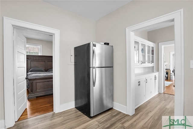 kitchen with stainless steel refrigerator, white cabinetry, and light hardwood / wood-style floors