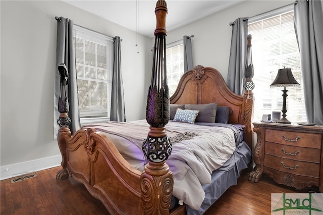 bedroom with dark hardwood / wood-style flooring and multiple windows