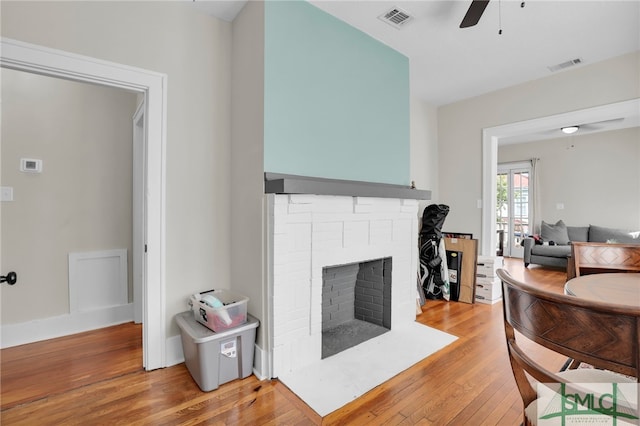 living room featuring ceiling fan, light wood-type flooring, and a fireplace