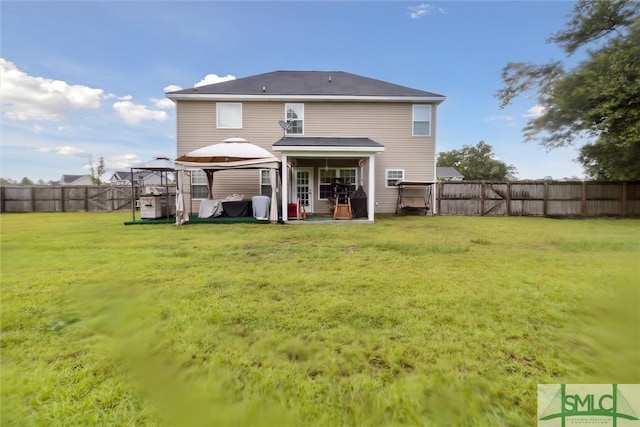 rear view of property featuring a yard and a gazebo