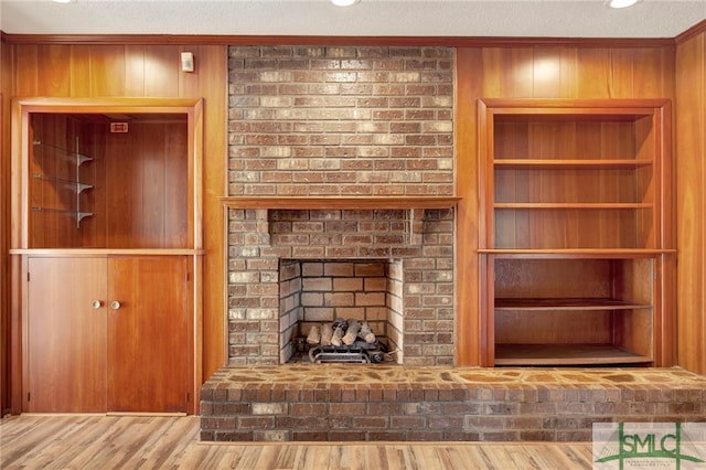 unfurnished living room featuring a textured ceiling, wooden walls, wood-type flooring, and a fireplace