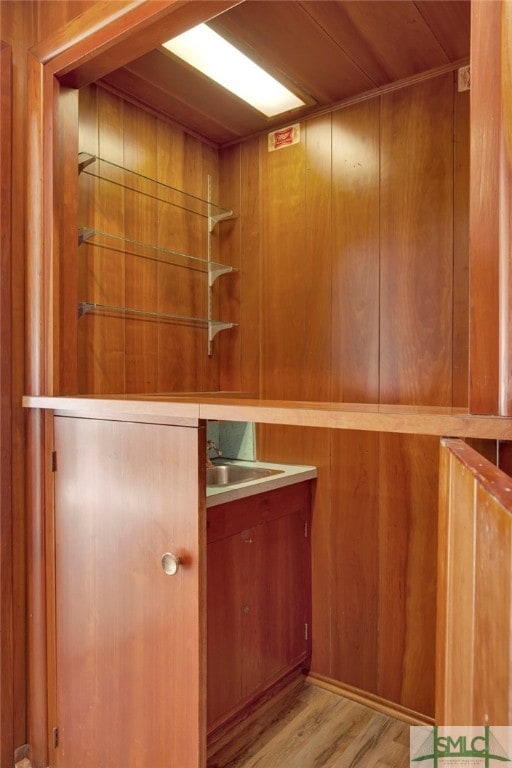 bar with light hardwood / wood-style flooring and wood walls