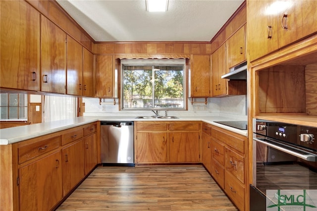 kitchen with kitchen peninsula, hardwood / wood-style floors, a textured ceiling, black appliances, and sink