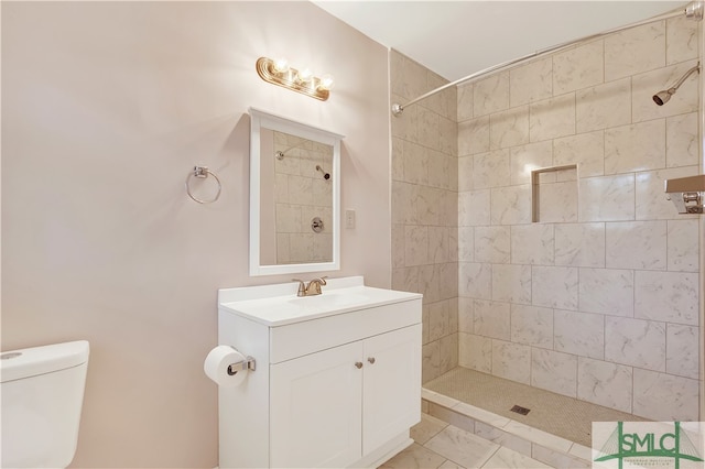 bathroom with vanity, tiled shower, and toilet