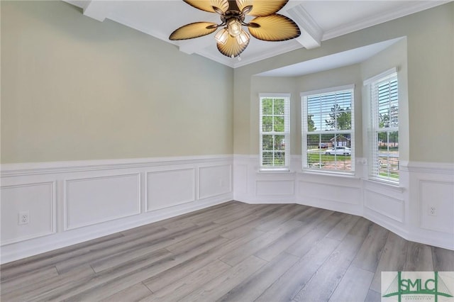 unfurnished room featuring ceiling fan, ornamental molding, a wainscoted wall, and wood finished floors