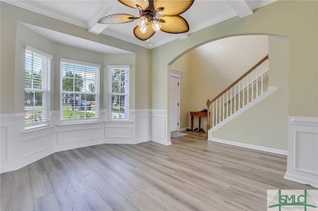 entryway with arched walkways, ornamental molding, beamed ceiling, and light wood-style floors