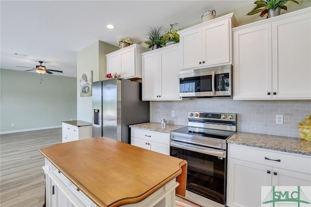 kitchen featuring appliances with stainless steel finishes, white cabinets, ceiling fan, and tasteful backsplash