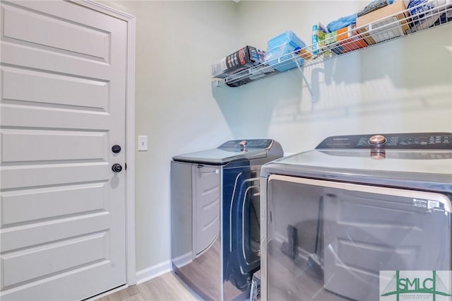 clothes washing area with laundry area, baseboards, light wood-style floors, and washer and dryer