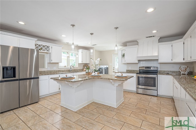 kitchen featuring pendant lighting, premium range hood, stainless steel appliances, light stone countertops, and a kitchen island