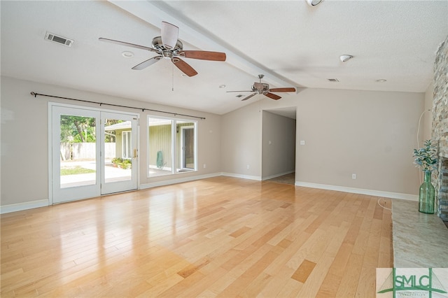 spare room with lofted ceiling with beams, a fireplace, and light wood-type flooring