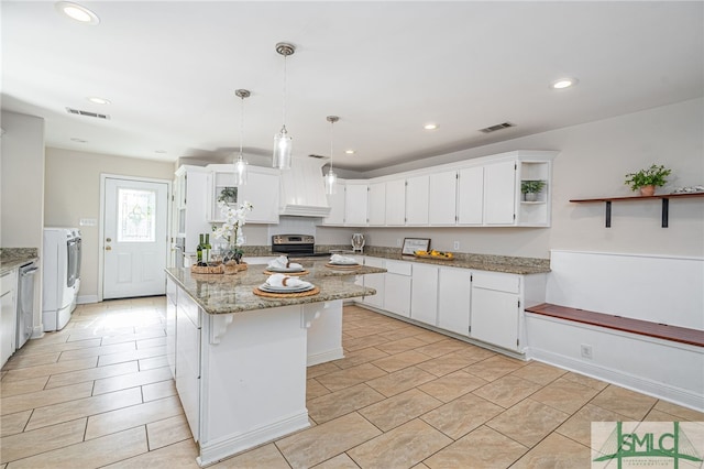 kitchen featuring white cabinetry, a center island, stainless steel appliances, light stone countertops, and washer and clothes dryer