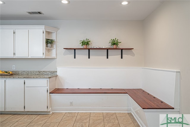 interior space featuring white cabinetry, light tile patterned floors, and light stone counters