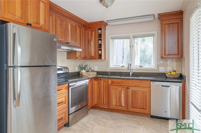 kitchen featuring sink, tasteful backsplash, light tile patterned floors, appliances with stainless steel finishes, and dark stone counters