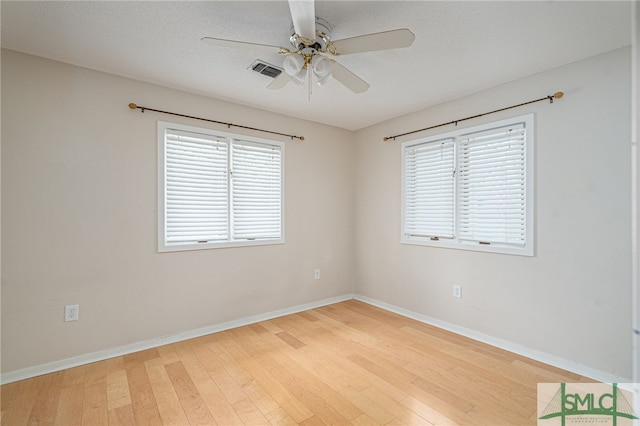 empty room featuring ceiling fan, light hardwood / wood-style flooring, and a textured ceiling