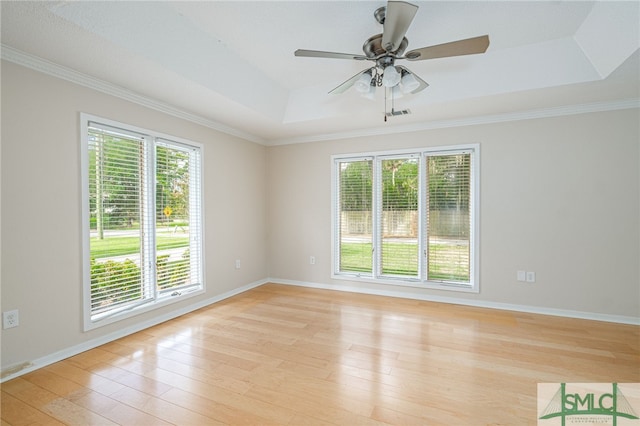 spare room with crown molding, ceiling fan, a tray ceiling, and light hardwood / wood-style flooring